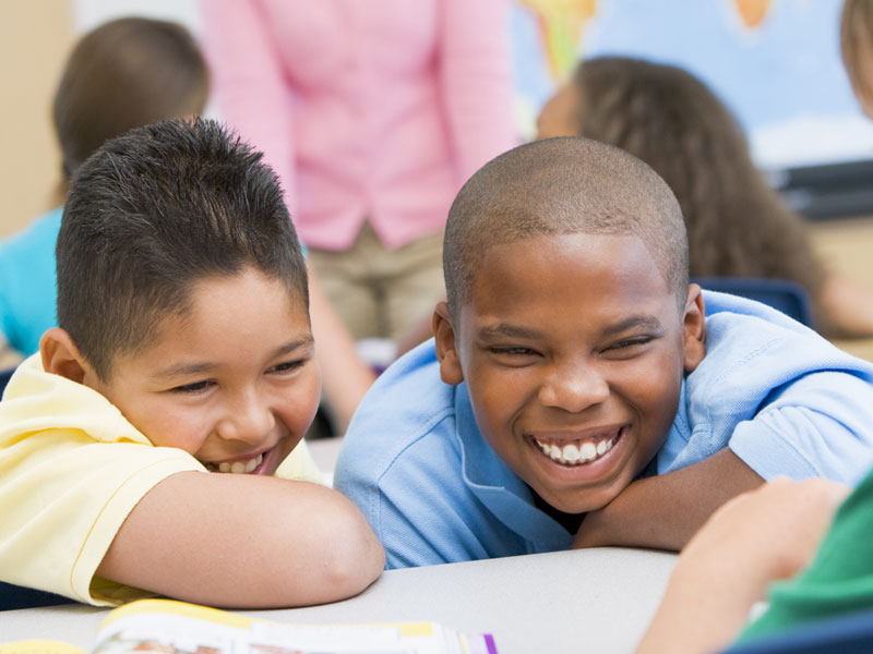 a photograph of two boys laughing while they bully someone