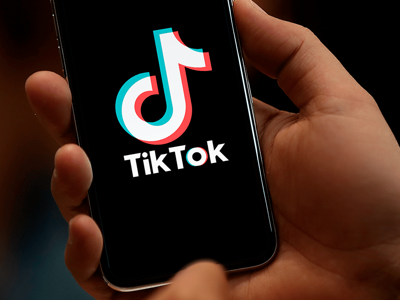 a hand holding a phone with the tik tok icon on the screen