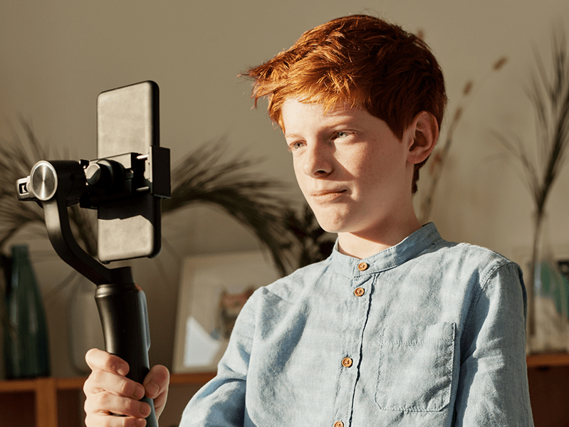 a boy takes a selfie with a phone on a handheld mount