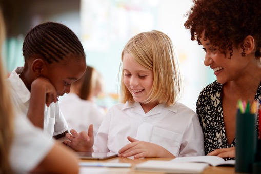 boy and girl using ipad and smiling with adult