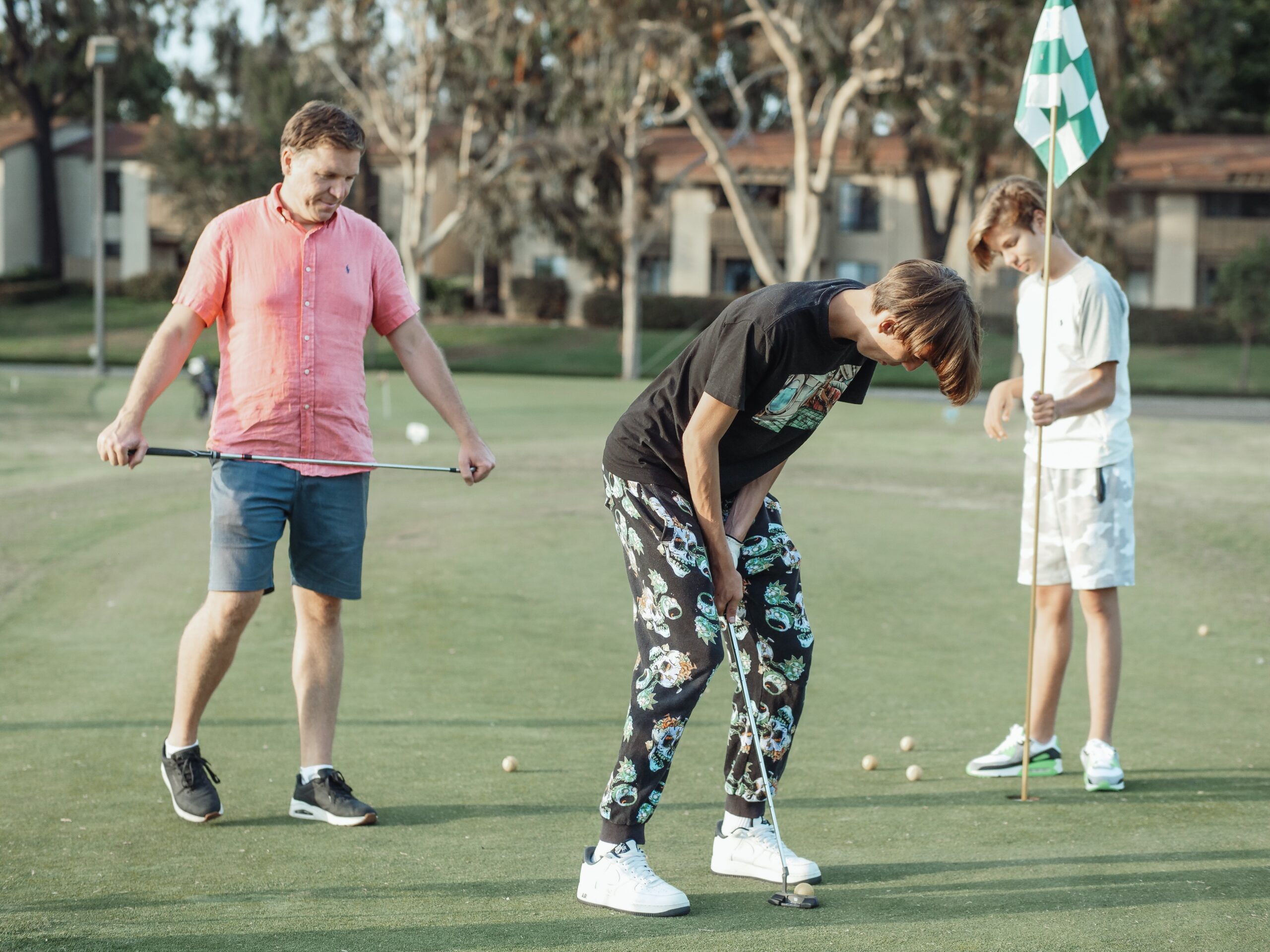 Father playing golf with his 2 teenage sons